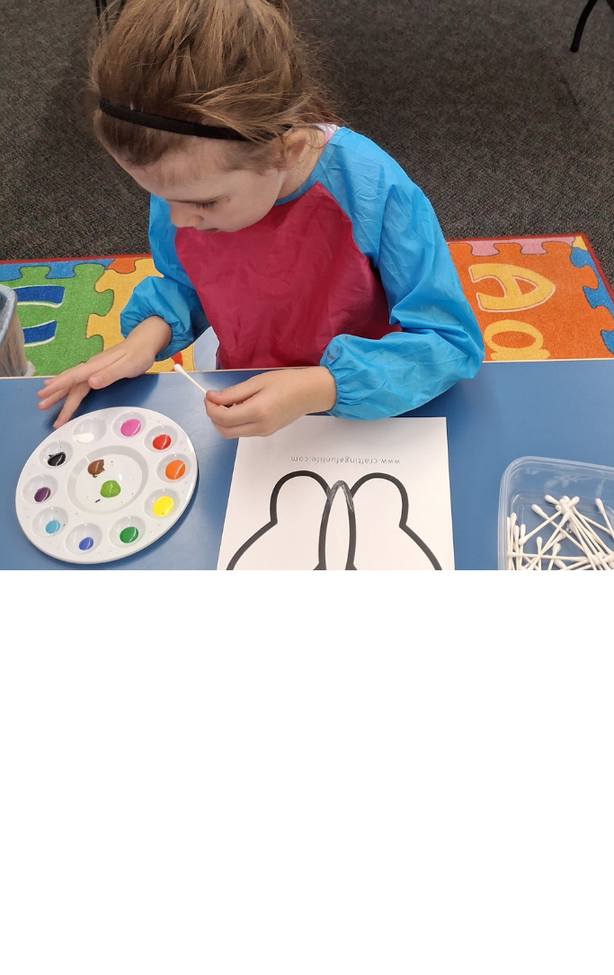 Girl painting a butterfly picture with Q-Tips and a variety of colors.